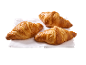 Tre gyllene croissanter på en vit servett.