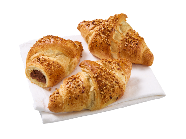 Tre nöttoppade croissanter, en fylld med choklad, på en vit servett.
