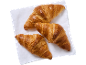 Tre gyllene, krispiga croissanter på en vit servett.