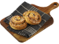 Två kanelbullar med pärlsocker på en träskärbräda och tygduk