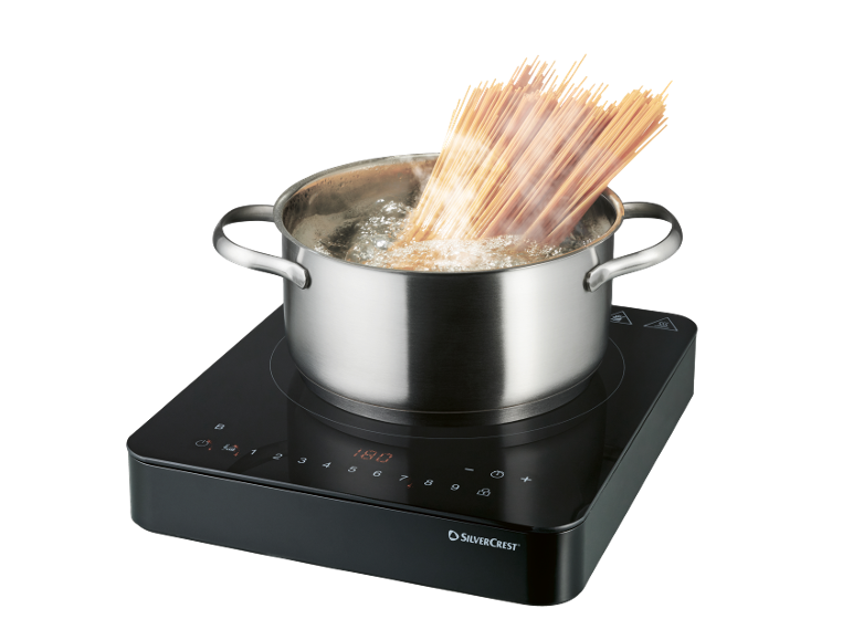 Induktionshäll med kastrull kokande vatten och spaghetti.