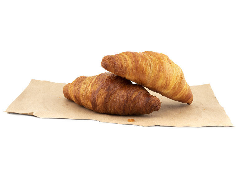 Två gyllene croissanter på bakplåtspapper.