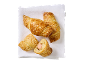 Gyldene croissanter med korv, strödda med sesamfrön, på en vit servett.