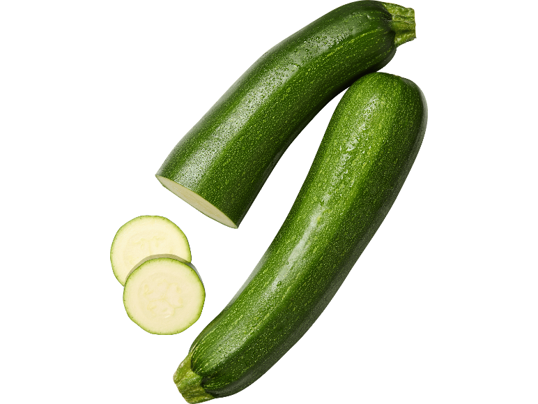 Färska gröna zucchini, en halverad och två skivor, mot svart bakgrund.