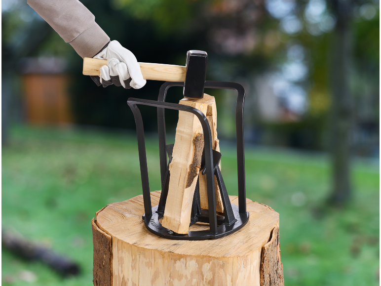 Slägga och vedklyv på en trädstubbe, med handskbeklädd hand som håller släggan.