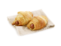 Två salta croissanter med korv och sesamfrön på en linneduk.