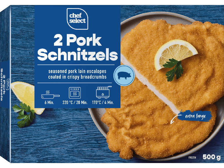 Två panerade fläskschnitzlar med citron och persilja på en tallrik.