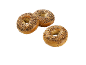 Tre krispiga bagels med fröblandning på svart bakgrund.