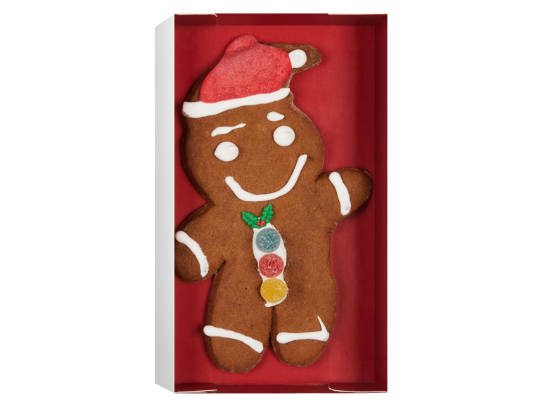 Julpepparkaksgubbe med tomteluva och godisdekoration i en röd låda.
