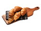 Fem gyllene croissanter på en grårutig duk och en träskärbräda.