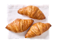 Tre gyllene croissanter på en vit linneservett.
