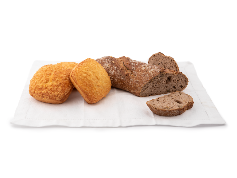 Ostbröd och fullkornsbröd på en vit duk.