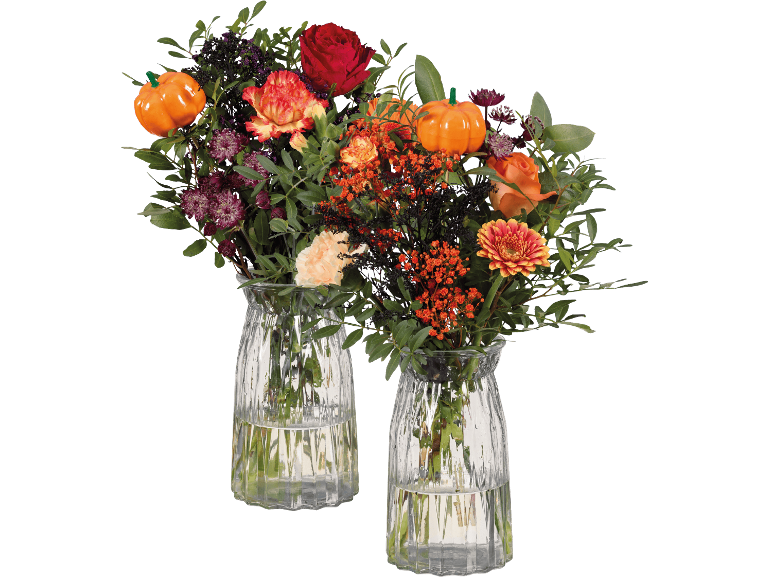 Två höstblombuketter i glasvaser med dekorativa pumpor.