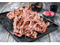 Pulled beef på en bakplåt med köttklor, sås och inlagd lök.