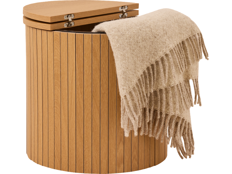 Förvaringspall i trä med en ljusbeige filt draperad över sidan.