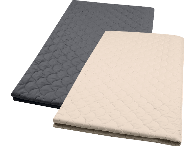 Två quiltade filtar i grått och beige, staplade på varandra.