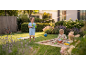 Barn leker i trädgården, pojke med vattenpistol, flicka i sandlåda.