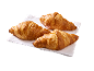 Tre gyllenbruna croissanter på en vit servett, redo att avnjutas.