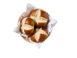 Tre kringelbullar i en flätad korg fodrad med en vit servett, ovanifrån.