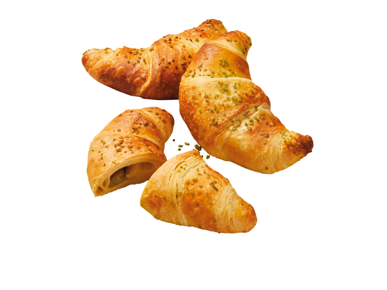 Fyra gyllene pistagecroissanter, en öppen med fyllning.