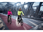 Par på elcyklar i reflexjackor på en bro.