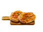 Två nybakade minipizzor med tomater och pesto på en skärbräda i trä.