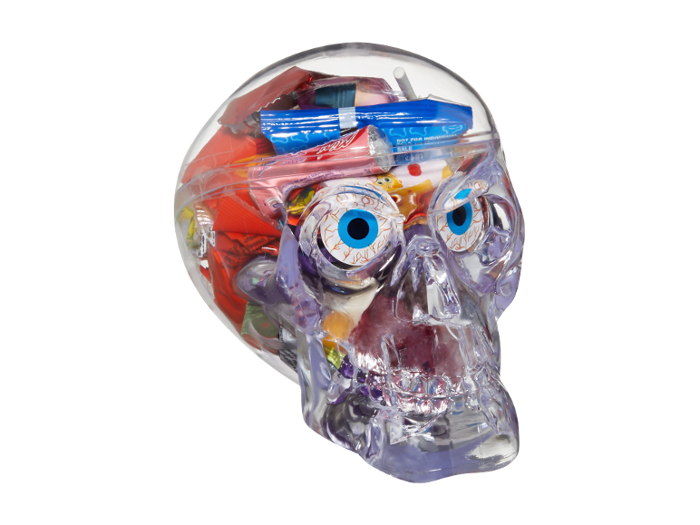 Genomskinlig dödskalle fylld med blandat Halloween-godis, inklusive geléögon och inslagna sötsaker.
