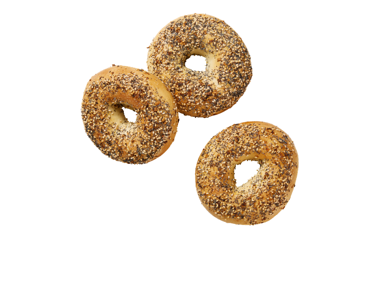 Tre krispiga bagels med allt-topping, strödda med frön, på svart bakgrund.