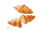 Två gyllene croissanter, en hel och en halverad, med smulor.