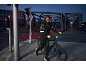 Man cyklar i staden på natten, bär en reflekterande cykeljacka och handskar.