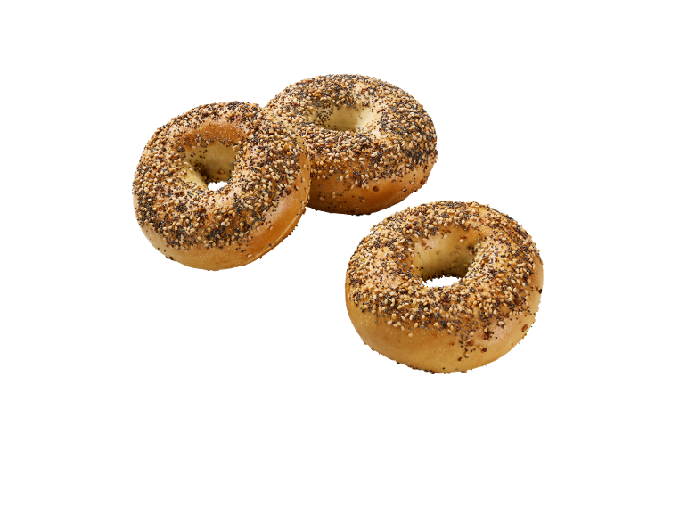 Tre krispiga bagels med fröblandning på svart bakgrund.