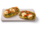 Två pesto- och tomatflatbröd med mozzarella på en rektangulär serveringsfat.
