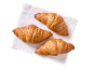Tre gyllenbruna croissanter på en vit servett, sedda ovanifrån.