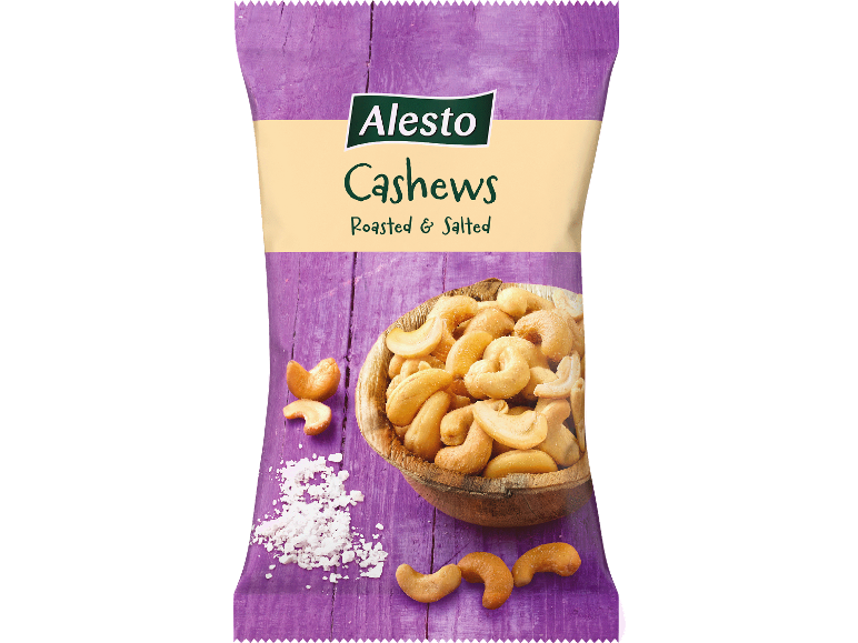 Påse med rostade och saltade cashewnötter med en skål cashewnötter och utspritt salt.