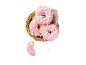 Rosa glaserade munkar med marshmallows i en flätad korg, en munk biten.