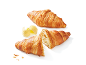 Gyllene croissanter med smör, en hel och en halverad.