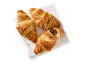 Tre croissanter med nötter på en vit handduk, en med chokladfyllning.