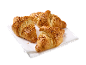 Tre croissanter med hackade nötter på en vit duk.