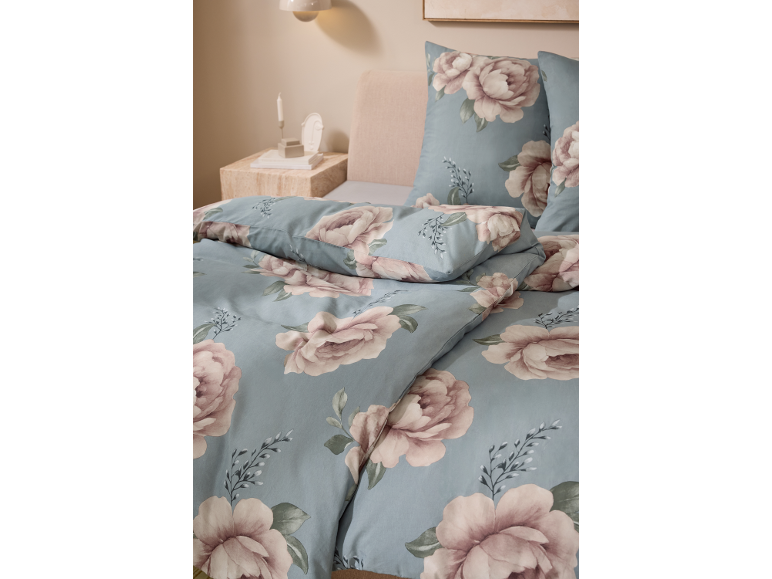 Blommigt påslakan och örngott i ett sovrum med sängbord och lampa.
