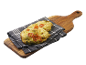 Focaccia med pesto och körsbärstomater på en träskärbräda och kökshandduk.