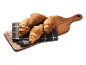 Fyra gyllene croissanter på en rutig duk på en träskärbräda.