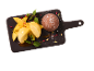 Dessert med färsk mango, mangoglass och en chokladboll på en bräda.