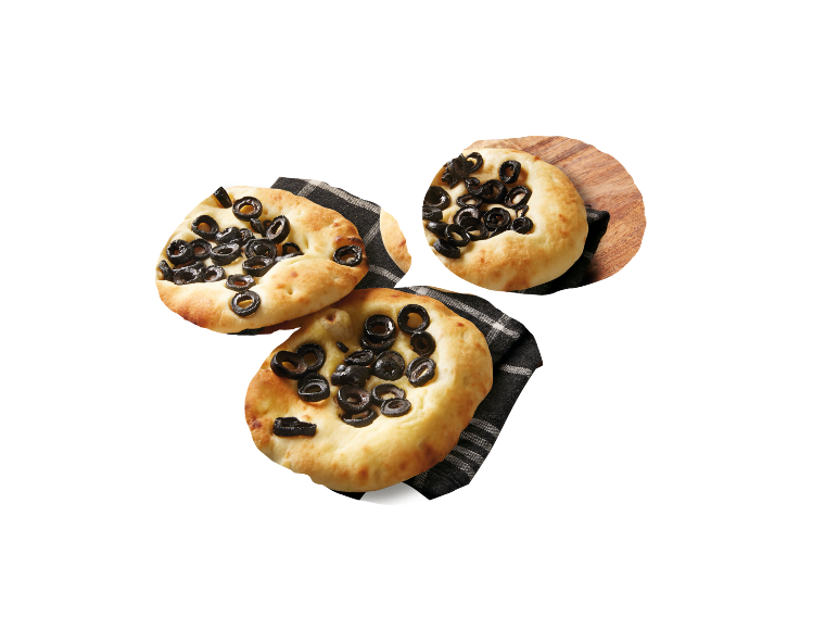 Focaccia med svarta oliver på en rutig duk och en träskiva.