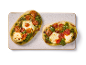 Två minipizzor med pesto, körsbärstomater och mozzarella på en rektangulär tallrik.