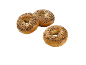 Tre krispiga bagels med fröblandning på svart bakgrund.