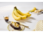 Färska bananer, en bit chokladkaka med banan och pistagenötter, och en kopp kaffe.
