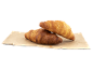 Två gyllene croissanter på bakplåtspapper.