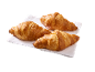 Tre gyllenbruna croissanter på en vit servett, redo att avnjutas.