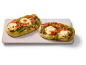 Två pesto- och tomatflatbröd med mozzarella på en rektangulär serveringsfat.