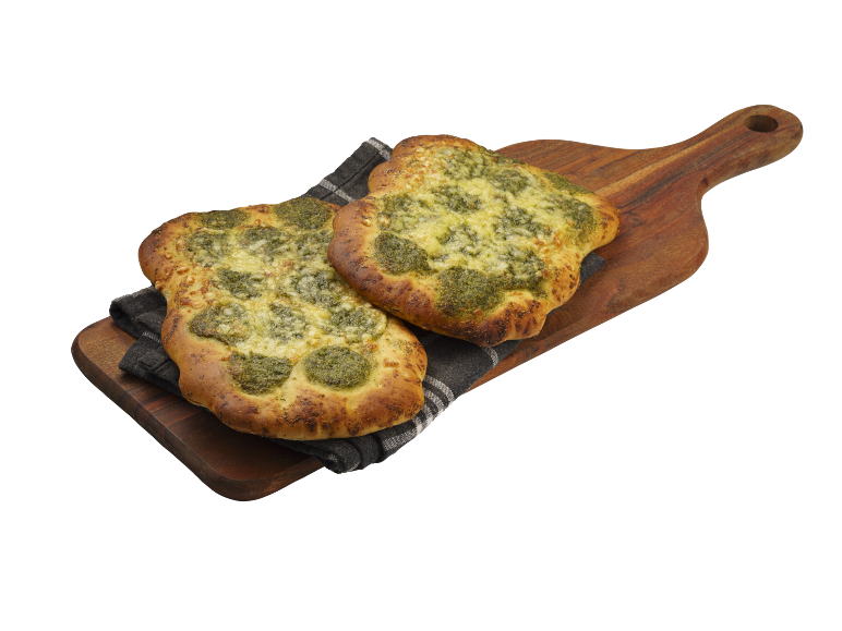 Pesto- och ostfocaccia på en träskärbräda med en duk.
